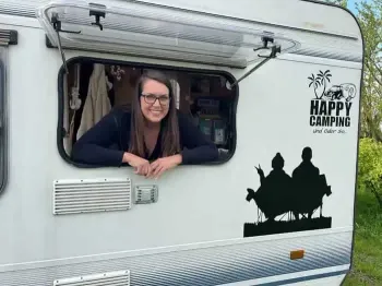 Wohnwagen-Fahrerin und Camping App-Nutzerin Melli guckt aus ihrem Wohnwagen