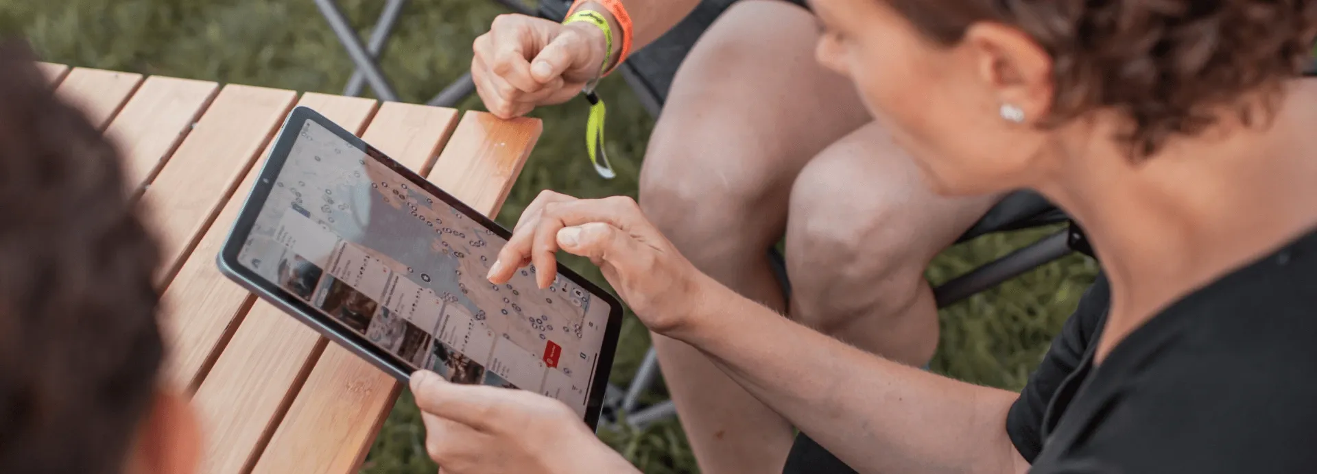 Jenny von der Camping App hält ein Tablet und erklärt darauf die App einer Nutzerin