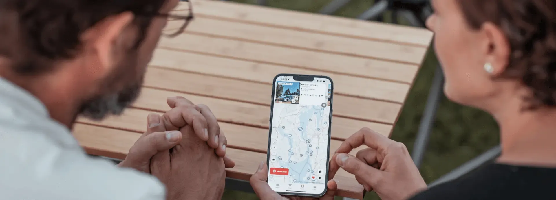 Camping App Ansicht auf dem Smartphone mit Lukas und Jenny daneben