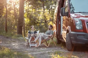 Jenny und Lukas von der Camping App sitzen im Sonnenuntergang vor ihrem Camper
