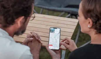 Jenny und Lukas schauen sich die Camping App auf dem Smartphone an