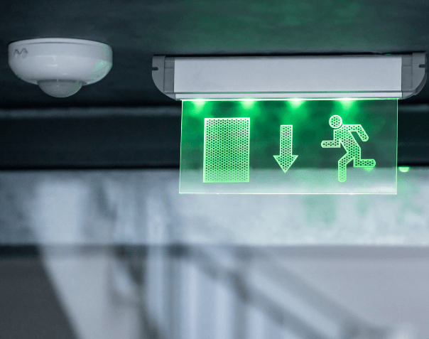 Couloir balisé par un panneau vert de sortie de secours