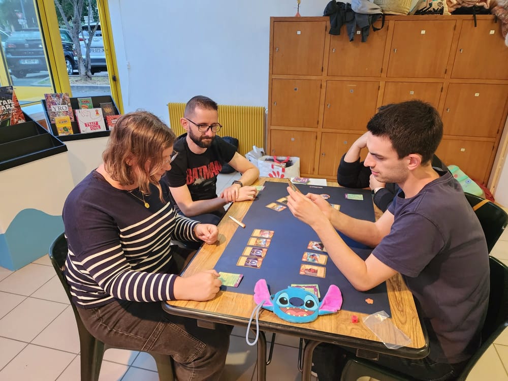 Une table concentrée autour du jeu de cartes Stitch en pleine mission de sauvetage