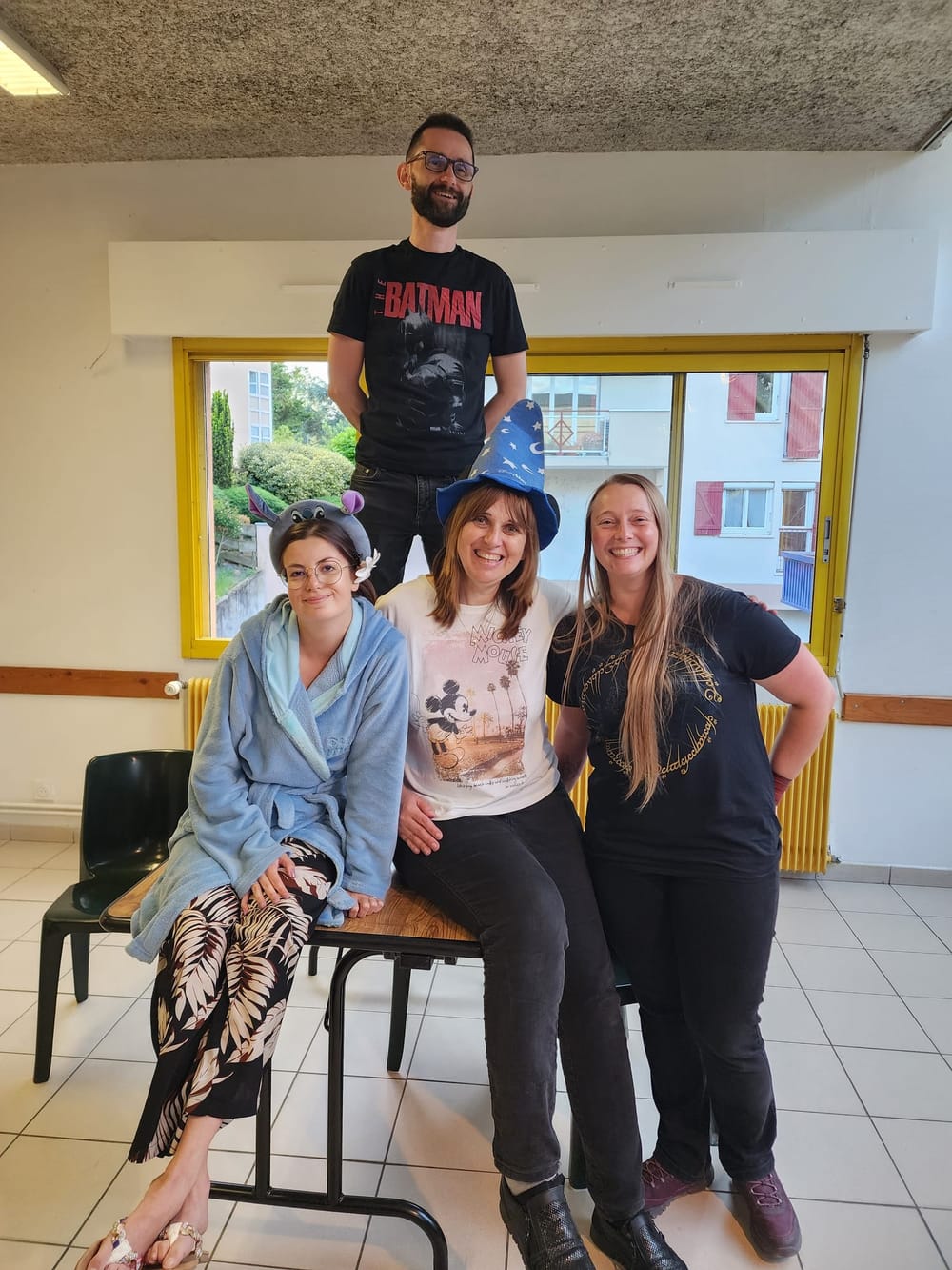 Batman prend de la hauteur sur une table entouré de ses acolytes en pyjama et chapeau de sorcier