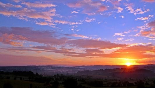 Lever de soleil sur un jour radieux, avec des nuages roses et mauves ; métaphore d'une convalescence.
