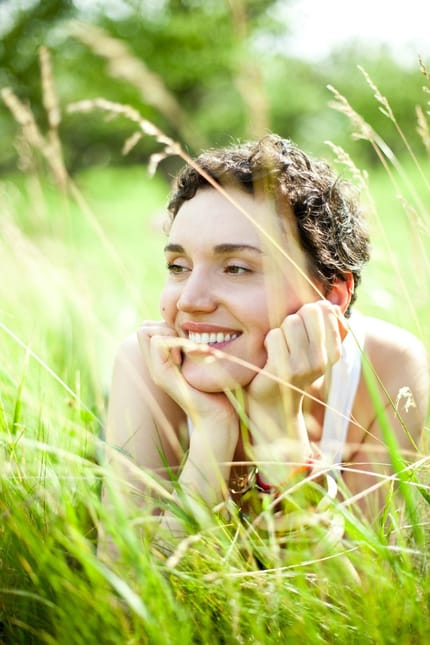 Une jeune femme se repose, allongée dans l'herbe haute.
