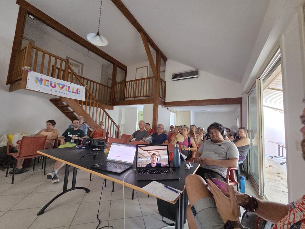 L'assemblée attentive dans la salle devant la vidéo de Thomas et les membres du bureau.