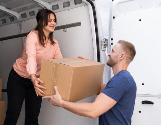 Zwei Menschen laden Umzugskarton aus Transporter aus